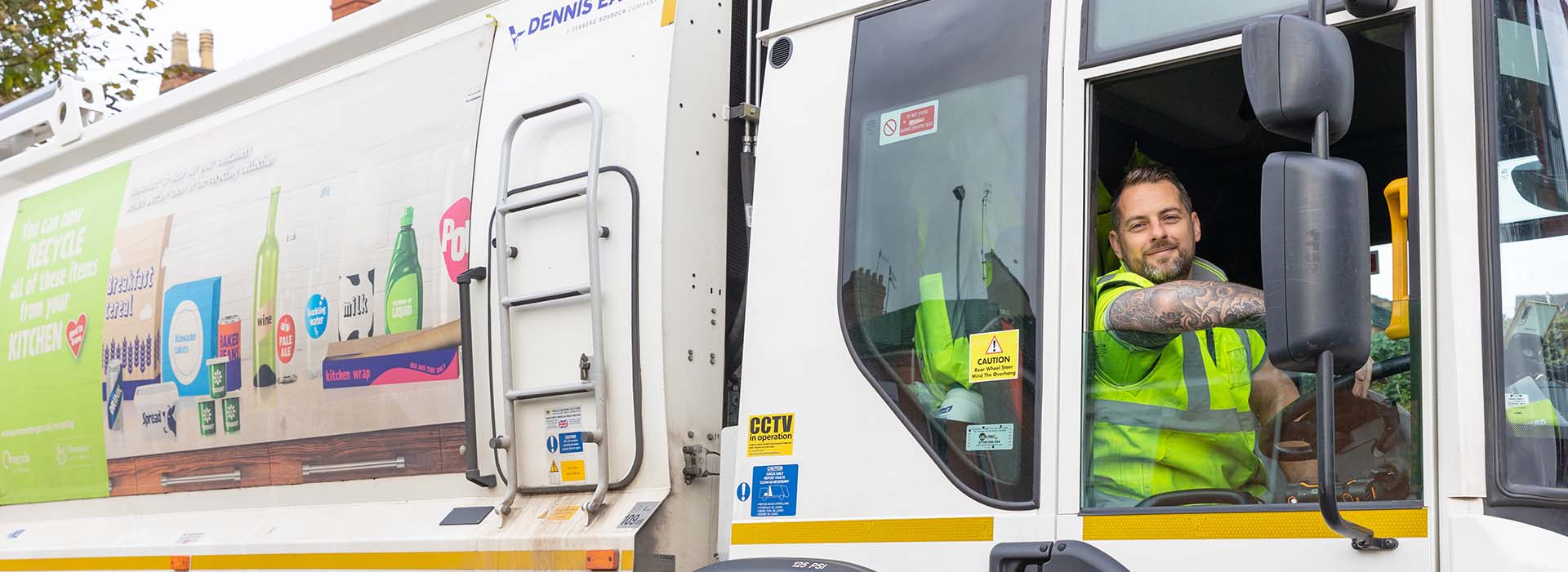 Man smiling sat in drivers seat of a bin collection lorry